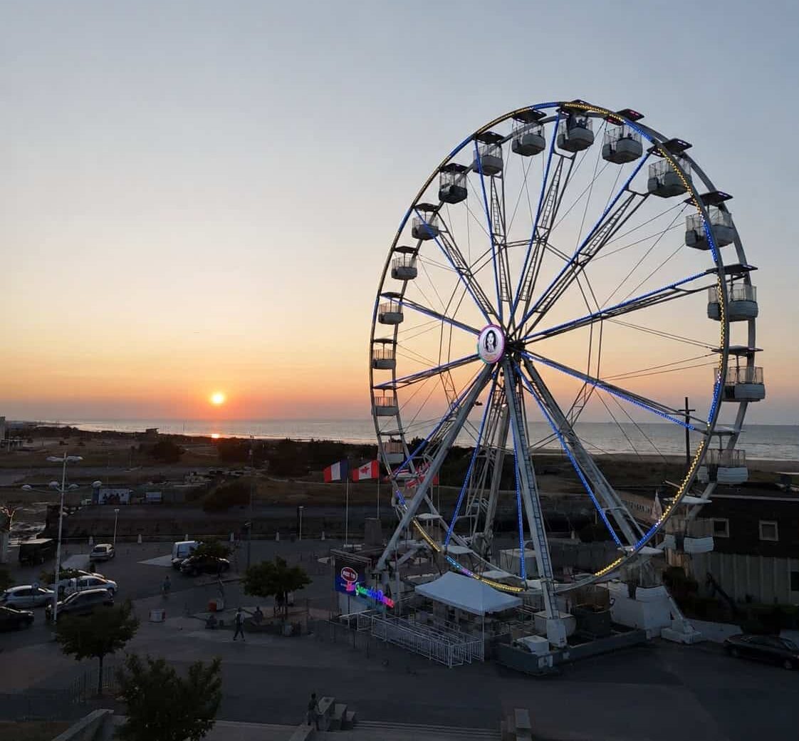 Grande roue illuminée au coucher de soleil face à la mer à Courseulles-sur-Mer